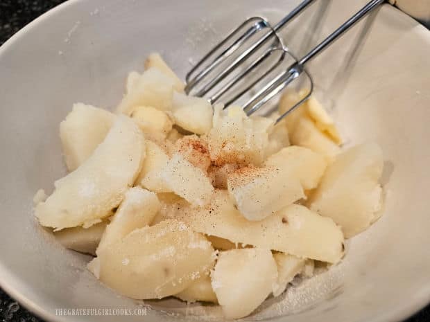 Butter and spices are added to drained potatoes and mashed well.