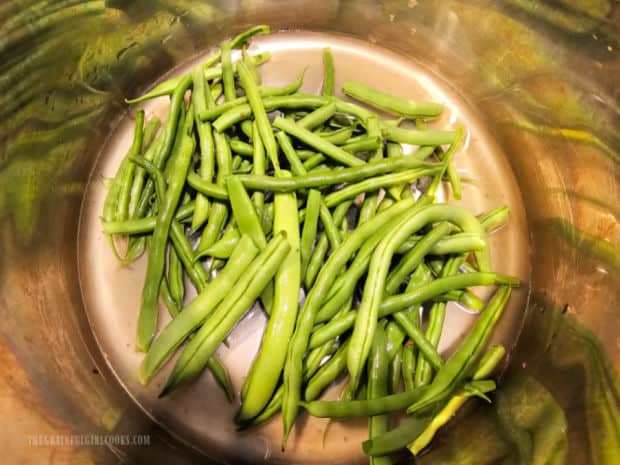 Broth is poured over the green beans in the Instant Pot.