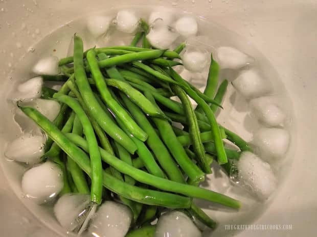 Microwaved green beans are placed in ice water after cooking to cool them.