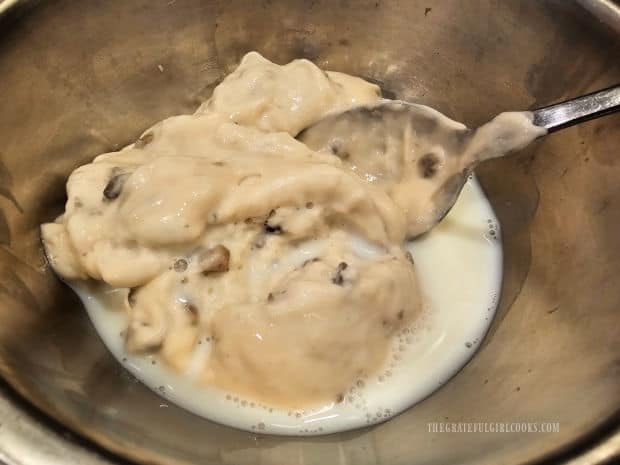 Cream of mushroom soup is combined with milk in a small bowl.