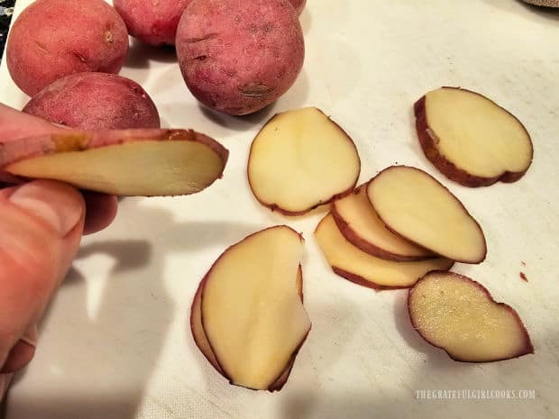 Small, unpeeled red potatoes are very thinly sliced for the casserole.