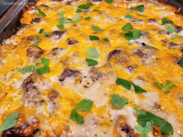 Cheesy beef potato casserole is garnished with parsley before serving.