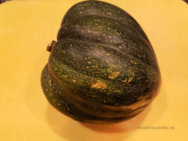 A medium sized acorn squash, ready to slice in half from top to bottom.