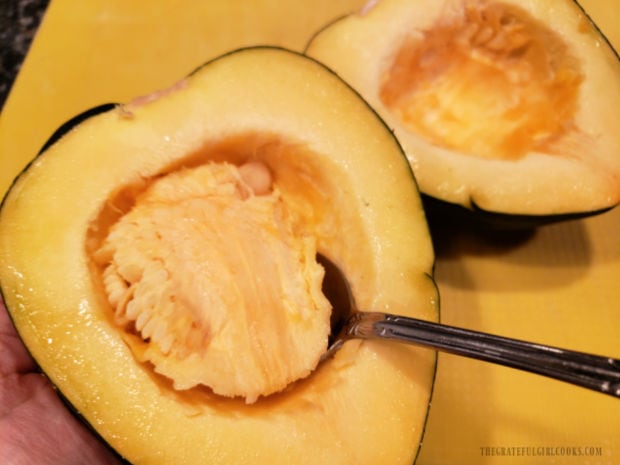 Seeds and stringy pith are scooped out of the raw squash's cavity.