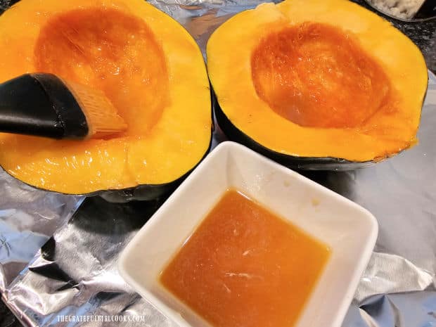 Squash halves are coated with butter honey mixture before baking.