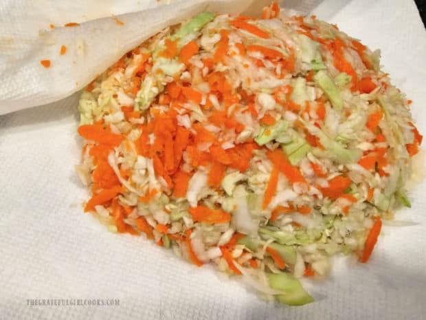 The grated carrot and cabbage are patted dry using paper towels.