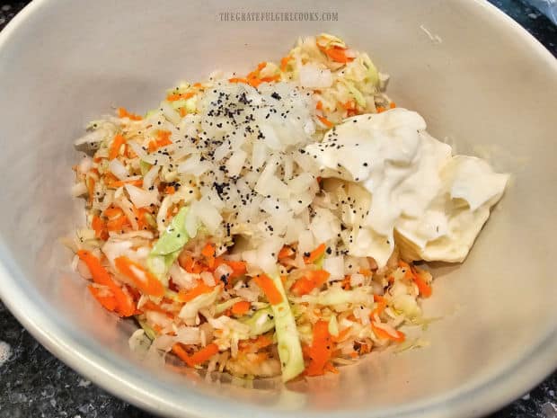 Mayonnaise, onion, sugar, salt, pepper and poppy seeds are added to the coleslaw mixture.