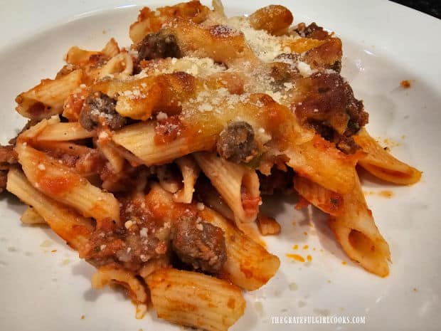 A portion of Italian penne pasta casserole, topped with Parmesan cheese for serving.