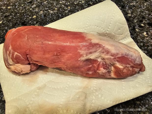 Pork tenderloin is patted dry using paper towels before it is seasoned.