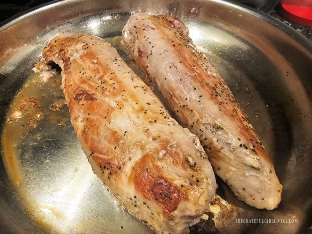 Two pork tenderloins in skillet after being pan-seared on all sides.