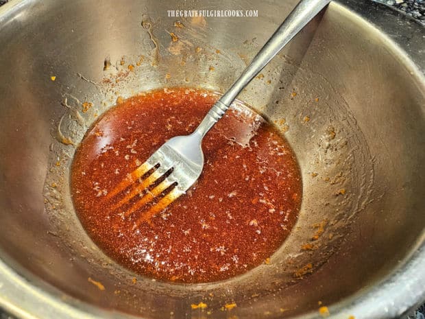 Glaze ingredients are stirred together in a metal bowl until fully combined.