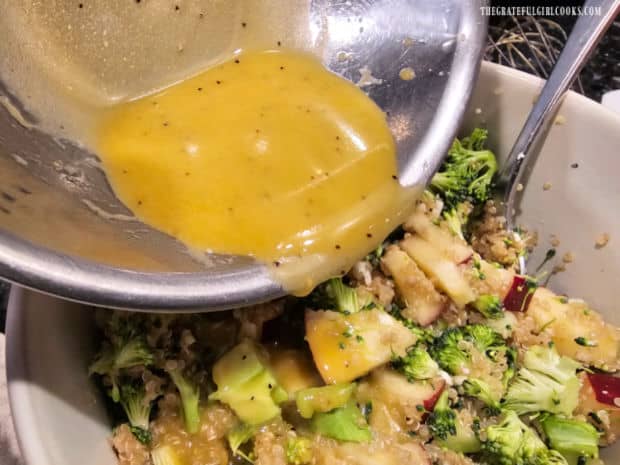 The salad dressing is poured over the broccoli apple quinoa salad and stirred to combine.