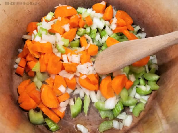 Chopped carrots, onions and celery are cooked in olive oil in a large soup pot.