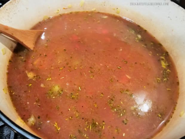 Diced tomatoes, vegetable broth and water are added to the soup pot of veggies.