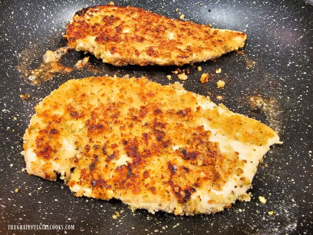 Chicken breasts are turned halfway through cooking to reveal browned crispy exterior.