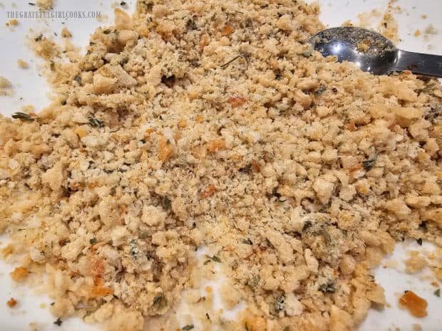 Seasoned breadcrumbs are spread on a plate, ready to coat the chicken.